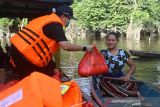 Direktur Perumdam Tirta Senentang Sintang Jane Elisabeth Wuysang (kiri) menyerahkan bantuan sembako untuk korban banjir di Sungai Rambai, Kabupaten Sintang, Kalimantan Barat, Kamis (25/11/2021). Perusahaan Umum Daerah Air Minum (Perumdam) Tirta Senentang mendistribusikan puluhan paket sembako yang merupakan kerjasama dengan Dewan Pimpinan Pusat dan Dewan Pimpinan Daerah Persatuan Perusahaan Air Minum se-Indonesia bagi korban banjir yang bermukim di hilir sungai di wilayah setempat. ANTARA FOTO/Jessica Helena Wuysang