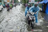 Pengendara mendorong sepeda motor yang mogok akibat genangan banjir di jalan Jakarta, Bandung, Jawa Barat, Jumat (26/11/2021). Kawasan tesebut kerap dilanda banjir saat intensitas hujan yang tinggi akibat drainase yang buruk sehingga menganggu arus lalu lintas. ANTARA FOTO/Novrian Arbi/agr