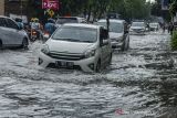 Pengendara melintasi genangan banjir di jalan Jakarta, Bandung, Jawa Barat, Jumat (26/11/2021). Kawasan tesebut kerap dilanda banjir saat intensitas hujan yang tinggi akibat drainase yang buruk sehingga menganggu arus lalu lintas. ANTARA FOTO/Novrian Arbi/agr