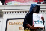 Peserta aksi melakukan teatrikal sambil membawa sejumlah berkas barang bukti korupsi ketika aksi di depan Kantor Kejaksaan Negeri Blitar, Jawa Timur, Selasa (30/11/2021). Selain dalam rangka peringatan hari anti korupsi pada 9 Desember mendatang, aksi tersebut menuntut adanya penuntasan penanganan kasus dugaan korupsi di wilayah itu. Antara Jatim/Irfan Anshori/zk