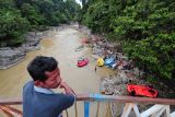 Seorang warga menyaksikan peserta Geo Fun Rafting Merangin 2021 menepi di garis finis Sungai Batang Merangin dalam Kawasan Geopark Merangin, Biuku Tanjung, Merangin, Jambi, Kamis (2/12/2021). Kegiatan yang diikuti puluhan peserta itu bertujuan untuk ikut menunjang usulan kawasan Geopark Merangin masuk dalam daftar UNESCO Global Geoparks (UGG). ANTARA FOTO/Wahdi Septiawan/tom. 