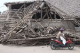 Seorang warga mengangkut barang yang bisa diselamatkan dari rumahnya yang hancur akibat erupsi gunung Semeru di desa Supiturang, Lumajang, Jawa Timur, Minggu (5/12/2021). Luncuran awan panas akibat letusan gunung Semeru mengakibatkan puluhan rumah di dua kecamatan rusak dan delapan kecamatan terdampak abu vulkanik. ANTARA FOTO/Ari Bowo Sucipto/foc.
