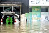 Warga duduk di atas mobil yang tergenang banjir di kawasan Legian, Kuta, Badung, Bali, Senin (6/12/2021). Hujan deras yang mengguyur wilayah Bali sejak Minggu (5/12) mengakibatkan banjir di sejumlah titik di kawasan Kuta dengan ketinggian air yang bervariasi. ANTARA FOTO/Fikri Yusuf/nym.