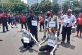 Buruh menggelar aksi teatrikal manusia silver dan pengusaha