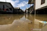 Seorang anak mengumpulkan botol bekas saat banjir pasang air laut atau rob di Desa Hagu Selatan, Kecamatan Banda Sakti, Lhokseumawe, Aceh, Senin (6/12/2021). Banjir rob musiman itu merendam tiga desa perkampungan nelayan dan merusak jalan lingkar pesisir pantai. ANTARA FOTO/Rahmad