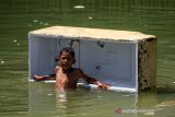 Seorang anak mengumpulkan botol bekas saat banjir pasang air laut atau rob di Desa Hagu Selatan, Kecamatan Banda Sakti, Lhokseumawe, Aceh, Senin (6/12/2021). Banjir rob musiman itu merendam tiga desa perkampungan nelayan dan merusak jalan lingkar pesisir pantai. ANTARA FOTO/Rahmad