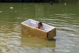 Seorang anak mengumpulkan botol bekas saat banjir pasang air laut atau rob di Desa Hagu Selatan, Kecamatan Banda Sakti, Lhokseumawe, Aceh, Senin (6/12/2021). Banjir rob musiman itu merendam tiga desa perkampungan nelayan dan merusak jalan lingkar pesisir pantai. ANTARA FOTO/Rahmad