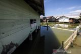 Seorang anak mengumpulkan botol bekas saat banjir pasang air laut atau rob di Desa Hagu Selatan, Kecamatan Banda Sakti, Lhokseumawe, Aceh, Senin (6/12/2021). Banjir rob musiman itu merendam tiga desa perkampungan nelayan dan merusak jalan lingkar pesisir pantai. ANTARA FOTO/Rahmad