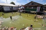 Seorang anak mengumpulkan botol bekas saat banjir pasang air laut atau rob di Desa Hagu Selatan, Kecamatan Banda Sakti, Lhokseumawe, Aceh, Senin (6/12/2021). Banjir rob musiman itu merendam tiga desa perkampungan nelayan dan merusak jalan lingkar pesisir pantai. ANTARA FOTO/Rahmad