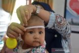 Petugas kesehatan mengukur lingkaran kepala anak balita pada kegiatan imunisasi anak di Puskesmas Desa Doy, Kecamatan Ulee Kareueng, Banda Aceh, Aceh, Jumat (10/12/2021). Kementerian Kesehatan meminta pemerintah daerah meningkatkan cakupan imunisasi dasar pada anak balita dan anak usia sekolah di tengah pandemi COVID-19 angkanya secara nasional  baru mencapai 58,4 persen per Oktober 2021 atau masih rendah dari target 79,1 persen. ANTARA FOTO/Ampelsa