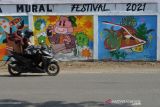 Pelajar mengendarai sepeda motor melintas di depan mural COVID-19 di kawasan Lampineueng, Banda Aceh, Aceh, Jumat (10/12/2021). Mural itu memberikan pesan dan sekaligus bentuk sosialisasi kepada warga agar mematuhi protokol kesehatan dalam upaya mencegah penyebaran COVID-19. ANTARA FOTO/Ampelsa