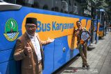 Gubernur Jawa Barat Ridwan Kamil (kiri) bersama Plt Bupati Kabupaten Bandung Barat Hengky Kurniawan (kanan) berfoto di samping bus operasional bagi buruh saat serah terima bus di Gedung Sate, Bandung, Jawa Barat, Senin (13/12/2021). Pemerintah Provinsi Jawa Barat memberikan bus operasional bagi buruh atau karyawan kepada dua kepala daerah yaitu Kabupaten Bandung Barat dan Kabupaten Indramayu guna meningkatkan pelayanan transportasi pekerja migran dan pekerja buruh. ANTARA FOTO/Raisan Al Farisi/agr