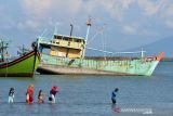 Warga mencari kerang dekat kapal ikan nelayan asing dengan nama KHF 1786 yang ditangkap terkait kasus ilegal fishing di Pelabuhan Perikanan Samudera (PPS) desa Lampulo, Banda Aceh, Aceh, Selasa (14/12/2021). Kementeria Kelautan dan Perikanan (KKP) menyatakan sepanjang tahun 2021 telah menangkap lebih dari sebanyak 166 kapal pencuri ikan asal Malaysia, Vietnam , Filipina dan kapal nelayan Indonesia terkait kasus pengunaan alat tangkap yang dilarang pukat  trawl, cantrang dan tidak memiliki izin penangkapan dari pemerintah Indonesia.  ANTARA FOTO/Ampelsa.