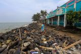 Warga berada di sekitar bangunan yang rusak akibat abrasi di pantai Eretan, Indramayu, Jawa Barat, Rabu (15/12/2021). Sejumlah kawasan di pantai tersebut mengalami abrasi akibat gelombang pasang air laut yang terjadi pada beberapa pekan terakhir. ANTARA FOTO/Dedhez Anggara/agr