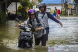 Warga mendorong sepeda motornya saat menorobos banjir yang merendam permukiman di Desa Bincau Muara, Kabupaten Banjar, Kalimantan Selatan, Senin (20/12/2021). Banjir akibat meluapnya sungai Martapura ditambah tingginya intensitas hujan mengakibatkan sejumlah desa di Kabupaten Banjar terendam banjir. Foto Antaranews Kalsel/Bayu Pratama S.