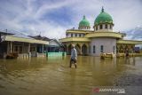 Warga melintasi banjir yang merendam permukiman di Desa Dalam Pagar Ulu, Kabupaten Banjar, Kalimantan Selatan, Senin (20/12/2021). Banjir yang disebabkan meluapnya sungai Martapura dan sungai Kiwa itu telah merendam sejumlah desa di enam Kecamatan di Kabupaten Banjar. Foto Antaranews Kalsel/Bayu Pratama S.