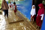 Sejumlah murid membersihkan halaman kelas yang terendam lumpur di SDN inpres Toabo, Mamuju, Sulawesi Barat, Senin (20/12/2021). Banjir yang terjadi Senin dini hari disebabkan tingginya intensitas hujan dan luapan air sungai yang merendam pemukiman warga, fasilitas umum dan sekolah di daerah tersebut. ANTARA FOTO/ Akbar Tado/hp.