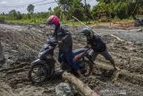 Warga mendorong sepeda motornya yang terjebak di jalan Trans Kalimantan yang rusak di Kecamatan Liang Anggang, Banjarbaru, Kalimantan Selatan, Senin (20/12/2021). Ruas jalan trans Kalimantan poros selatan yang sedang dalam progres pekerjaan rehabilitasi jalan tersebut rusak parah akibatnya aktivitas warga terganggu. Foto Antaranews Kalsel/Bayu Pratama S.