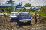 Warga melihat mobilnya yang terjebak di jalan Trans Kalimantan yang rusak di Kecamatan Liang Anggang, Banjarbaru, Kalimantan Selatan, Senin (20/12/2021). Ruas jalan trans Kalimantan poros selatan yang sedang dalam progres pekerjaan rehabilitasi jalan tersebut rusak parah akibatnya aktivitas warga terganggu. Foto Antaranews Kalsel/Bayu Pratama S.