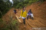 Warga berjalan melintas tanah longsor yang menutup jalan antardesa di Desa Datar Ajab, Kabupaten Hulu Sungai Tenagah, Kalimantan Selatan, Senin (20/12/2021). Tanah longsor akibat tingginya intensitas hujan mengakibatkan akses mobilitas masyarakat pedalaman Pegunungan Meratus yang dihuni 100 jiwa lebih itu terganggu. Foto Antaranews Kalsel/Bayu Pratama S.