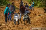 Warga menggunakan roda dua berjibaku saat melintas tanah longsor yang menutup jalan antardesa di Desa Datar Ajab, Kabupaten Hulu Sungai Tenagah, Kalimantan Selatan, Senin (20/12/2021). Tanah longsor akibat tingginya intensitas hujan mengakibatkan akses mobilitas masyarakat pedalaman Pegunungan Meratus yang dihuni 100 jiwa lebih itu terganggu. Foto Antaranews Kalsel/Bayu Pratama S.