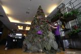 Pekerja menghias pohon Natal dengan lampu hias di Quest Hotel Darmo, Surabaya, Jawa Timur, Senin (20/12/2021). Pohon Natal setinggi 3,5 meter dan terbuat dari 121 daun jati kering itu untuk menyambut perayaan Hari Natal 2021. Antara Jatim/Didik Suhartono/zk