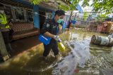 Petugas kesehatan membawa box vaksin melintasi banjir yang merendam rumah warga di Desa Mekar, Kabupaten Banjar, Kalimantan Selatan, Selasa  (21/12/2021). Dinas Kesehatan Kabupaten Banjar bersama Polsek Martapura Timur melakukan vaksinasi COVID-19 dari rumah ke rumah ditengah banjir untuk meningkatkan capaian target vaksin serta mencapai kekebalan komunal menuju Indonesia sehat bebas COVID-19. Foto Antaranews Kalsel/Bayu Pratama S.