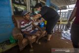 Petugas kesehatan menyuntikan vaksin COVID-19 kepada warga di rumahnya yang terendam banjir di Desa Mekar, Kabupaten Banjar, Kalimantan Selatan, Selasa (21/12/2021). Dinas Kesehatan Kabupaten Banjar bersama Polsek Martapura Timur melakukan vaksinasi COVID-19 dari rumah ke rumah ditengah banjir untuk meningkatkan capaian target vaksin serta mencapai kekebalan komunal menuju Indonesia sehat bebas COVID-19. Foto Antaranews Kalsel/Bayu Pratama S.