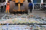 Petugas mengoperasikan alat berat untuk menghancurkan ribuan botol minuman keras di Alun-alun Indramayu, Jawa Barat, Rabu (22/12/2021). Jelang Natal dan Tahun Baru, Polres Indramayu bersama Dinas Satpol PP dan Pemadam Kebakaran memusnahkan 11.209 botol minuman keras dan 1.187 liter tuak hasil operasi pekat selama tahun 2021. ANTARA FOTO/Dedhez Anggara/agr