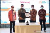 Pemimpin Divisi Bisnis Korporasi 3 BNI Rudy Sihombing (kedua kiri) bersama Direktur Keuangan & Manajemen Risiko Telkomsel Mohamad Ramzy (kedua kanan), menunjukkan berkas perjanjian kerja sama antara BNI dengan Telkomsel disaksikan Direktur Corporate Banking BNI Silvano Rumantir (kiri) dan POH Head of Corporate Finance Telkomsel Hendrianto Nasution (kanan) di Jakarta, Rabu (29/12/2021). Kerja sama tersebut untuk memberikan fasilitas Supply Chain Financing yang diyakini dapat meningkatkan efisiensi dan profit korporat melalui 