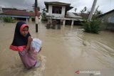 Sejumlah warga berjalan menembus banjir yang melanda Kota Lhoksukon, Aceh Utara, Aceh, Senin (3/1/2022). Data dari Badan Penanggulangan Bencana Daerah (BPBD) Aceh Utara mencatat banjir yang merendam 14 Kecamatan di daerah tersebut mengakibatkan 2.278 jiwa terdampak dan satu orang anak meninggal dunia. ANTARA FOTO/Rahmad