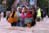 Sejumlah warga berjalan menembus banjir yang melanda Kota Lhoksukon, Aceh Utara, Aceh, Senin (3/1/2022). Data dari Badan Penanggulangan Bencana Daerah (BPBD) Aceh Utara mencatat banjir yang merendam 14 Kecamatan di daerah tersebut mengakibatkan 2.278 jiwa terdampak dan satu orang anak meninggal dunia. ANTARA FOTO/Rahmad