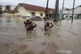 Sejumlah warga berjalan menembus banjir yang melanda Kota Lhoksukon, Aceh Utara, Aceh, Senin (3/1/2022). Data dari Badan Penanggulangan Bencana Daerah (BPBD) Aceh Utara mencatat banjir yang merendam 14 Kecamatan di daerah tersebut mengakibatkan 2.278 jiwa terdampak dan satu orang anak meninggal dunia. ANTARA FOTO/Rahmad