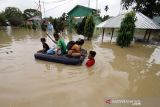 Sejumlah warga berjalan menembus banjir yang melanda Kota Lhoksukon, Aceh Utara, Aceh, Senin (3/1/2022). Data dari Badan Penanggulangan Bencana Daerah (BPBD) Aceh Utara mencatat banjir yang merendam 14 Kecamatan di daerah tersebut mengakibatkan 2.278 jiwa terdampak dan satu orang anak meninggal dunia. ANTARA FOTO/Rahmad