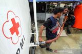 Relawan Palang Merah Indonesia (PMI) membagikan air untuk warga terdampak banjir di Desa Ketapang, Aceh Utara, Aceh, Kamis (6/1/2022). PMI Aceh Utara memberikan bantuan air bersih, kain sarung, selimut, kelambu dan pakaian laik pakai kepada korban banjir di daerah tersebut. ANTARA FOTO/Rahmad