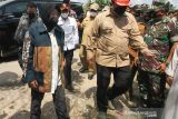 Menteri Sosial Tri Rismaharini berjalan menuju rumah ahli waris korban bencana banjir di Desa Meuria, Kecamatan Matang Kuli, Aceh Utara, Aceh, Selasa (11/1/2022). Mensos menyerahkan bantuan tanggap darurat senilai Rp1.9 miliar untuk membantu 52 ribu lebih korban banjir Aceh Utara, Aceh Timur, dan Aceh Tamiang. ANTARA FOTO/Rahmad