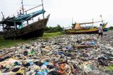 Nelayan beraktivitas di dekat tumpukan sampah yang berserakan di Pantai Dadap, Indramayu, Jawa Barat, Sabtu (15/1/2022). Sampah yang sebagian besar dari limbah rumah tangga dan plastik tersebut terseret arus dan menumpuk di pantai sehingga mengganggu aktivitas nelayan. ANTARA FOTO/Dedhez Anggara/agr