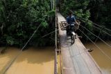 Pengendara sepeda motor melintasi jembatan gantung di Desa Aur Berduri, Nalo Tantan, Merangin, Jambi, Jumat (14/1/2022). Kementerian Pekerjaan Umum dan Perumahan Rakyat (PUPR) merencanakan pembangunan 73 jembatan gantung pada 2022 guna mempermudah mobilitas orang, jasa, dan logistik. ANTARA FOTO/Wahdi Septiawan/nz.