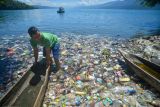 Warga memindahkan biduk di antara sampah di tepian Danau Singkarak, Nagari Sumpu, Kabupaten Tanah Datar, Sumatera Barat, Kamis (20/1/2022). Tepian danau wisata tersebut dipenuhi sampah plastik sejak sepekan terakhir yang menyulitkan nelayan mencari ikan. ANTARA FOTO/Iggoy el Fitra/tom.