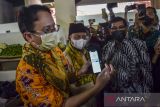 Wakil Menteri Perdagangan Jerry Sambuaga (kiri) didampingi Wakil Gubernur Jawa Barat Uu Ruzhanul Ulum (tengah) dan Wali Kota Tasikmalaya Muhammad Yusuf (kanan) memperlihtakan transaksi Qris di Pasar Rakyat Pancasila, Kota Tasikmalaya, Jawa Barat, Sabtu (22/1/2022). Wakil Menteri Perdagangan Jerry Sambuaga meresmikan pasar rakyat Pancasila yang sudah direvitalisasi dari bantuan Pemerintah Provinsi Jawa Barat sebanyak Rp15 miliar dan sekaligus meninjau harga kebutuhan pokok. ANTARA FOTO/Adeng Bustomi/agr