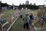 Pengunjung melihat foto yang dipajang pada pameran foto hasil karya Mahasiswa FISIP Unimal di kompleks Museum Lhokseumawe, Aceh, Senin (24/1/2022). Pameran yang menampilkan 274 karya foto mahasiswa ilmu komunikasi FISIP Unimal tersebut mengusung tema Aceh Bangkit Melawan COVID-19 dan berlangsung hingga 26 Januari 2022. ANTARA FOTO/Rahmad