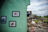 Sejumlah lukisan karya anak terdampak penggusuran dipamerkan diantara reruntuhan bangunan di Jalan Anyer Dalam, Bandung, Jawa Barat, Jumat (28/1/2022). Pameran karya seni yang diinisiasi oleh Rumah Bintang dengan tema 