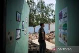 Pengunjung mengamati lukisan karya anak terdampak penggusuran yang dipamerkan diantara reruntuhan bangunan di Jalan Anyer Dalam, Bandung, Jawa Barat, Jumat (28/1/2022). Pameran karya seni yang diinisiasi oleh Rumah Bintang dengan tema 