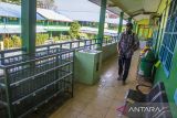 Petugas menyemprotkan cairan disinfektan di area sekolah SMP Negeri 1 Banjarmasin, Kalimantan Selatan, Senin (31/1/2022). Dinas Pendidikan Kota Banjarmasin menghentikan sementara Pembelajaran Tatap Muka (PTM) selama tujuh hari kedepan di SMPN 1, 2 dan 19 Banjarmasin setelah 12 siswa terkonfirmasi positif COVID-19. Foto Antaranews Kalsel/Bayu Pratama S.