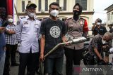 Polisi menyaksikan pemilik motor memotong knalpot tidak standar atau knalpot brong saat rilis penindakan di Polres Lhokseumawe, Aceh, Senin (7/2/2022). Polisi memusnahkan 34 knalpot brong hasil razia sebagai bentuk tindakan tegas agar pengendara mematuhi tata tertib lalu lintas dan tidak mengganggu kenyamanan warga. ANTARA FOTO/Rahmad