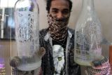 Perajin menunjukkan kerajinan ukiran di botol kaca di Padang, Sumatera Barat, Senin (14/2/2022). Kerajinan seni ukir pada botol kaca bekas tersebut dijual seharga Rp80 ribu hingga Rp400 ribu per botol. ANTARA FOTO/Muhammad Arif Pribadi/Lmo/wsj.
