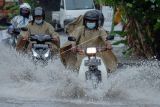 Sejumlah pengendara sepeda motor menerobos banjir yang menggenangi kawasan Jalan Gunung Salak, Denpasar, Bali, Senin (21/2/2022). Balai Besar Meteorologi Klimatologi dan Geofisika (BMKG) Wilayah III Denpasar mengeluarkan peringatan dini cuaca ekstrem yakni hujan lebat disertai petir atau kilat dan angin kencang berdurasi singkat di sebagain besar wilayah Bali yang berlaku selama 24 jam yakni pada 21 Februari 2022, pukul 08.00 Wita hingga 22 Februari 2022, pukul 08.00 Wita. ANTARA FOTO/Nyoman Hendra Wibowo/nym.