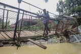 Warga memaksakan diri melintasi jembatan rusak di Desa Sukarasa, Tanjung Sari, Kabupaten Bogor, Jawa Barat, Kamis (24/2/2022).Jembatan penghubung antara Desa Sukarasa dan Desa Cibadak tersebut rusak parah yang disebabkan luapan banjir Sungai Cisero beberapa waktu lalu dan mengakibatkan akses kedua desa tersebut terputus. ANTARA FOTO/Yulius Satria Wijaya/rwa.