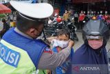 Anggota Satlantas Polres Karawang membantu memakaikan masker kepada seorang anak saat Operasi Keselamatan Lodaya 2022 di Karawang, Jawa Barat, Selasa (1/3/2022). Operasi Lodaya tersebut ditujukan untuk menurunkan Lakalantas, pelanggaran lalu lintas serta penerapan protokol kesehatan agar masyarakat tertib dalam berlalu lintas di masa pandemi COVID-19. ANTARA FOTO/M Ibnu Chazar/agr