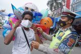 Anggota Satlantas Polres Karawang membantu memakaikan masker kepada warga pengguna jalan saat Operasi Keselamatan Lodaya 2022 di Karawang, Jawa Barat, Selasa (1/3/2022). Operasi Lodaya tersebut ditujukan untuk menurunkan Lakalantas, pelanggaran lalu lintas serta penerapan protokol kesehatan agar masyarakat tertib dalam berlalu lintas di masa pandemi COVID-19. ANTARA FOTO/M Ibnu Chazar/agr